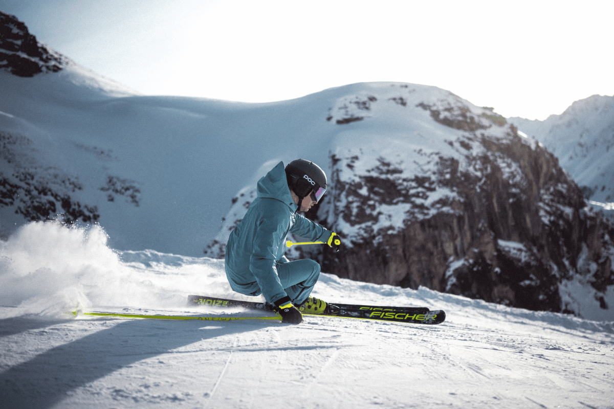 Skifahrer carvt auf Fischer Ski in den Alpen
